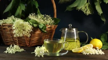 Kadın eli, yaşlı çiçeklerin çayına dilimlenmiş limon koyuyor.