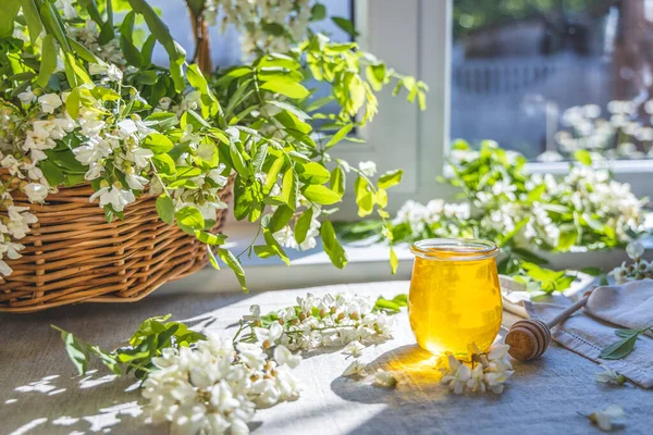 Tatlı bal kavanozu bahar akasyası çiçeklerini sarmıştı. Güneşli ışık, alanın sığ derinliği.