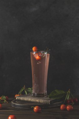 Bir bardak kiraz ya da limonata suyu, üzerine su sıçratılmış, taze kiraz ya da böğürtlen. Koyu kırsal ahşap yüzey