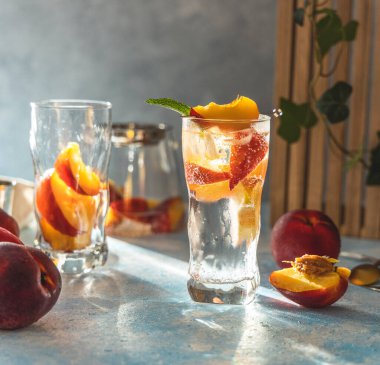 Soğuk şeftalili kokteyl ya da naneli buzlu çay. Güneşli ışık, açık beton masa yüzeyi. Alanın sığ derinliği, kapat, metin için alanı kopyala.