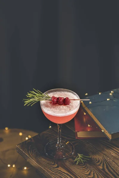 Elegant glass of raspberry cocktail with egg, decoration fresh berries on rosemary branch. Club cocktail. Sour drink with gin, raspberries, and egg white foam. Close up, shallow depth of the field.