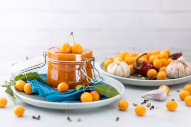 Cam kavanoz ev yapımı DIY doğal konserve sarı kiraz soslu acı biberli turşu veya beyaz masada duran seçici odaklı tkemali..