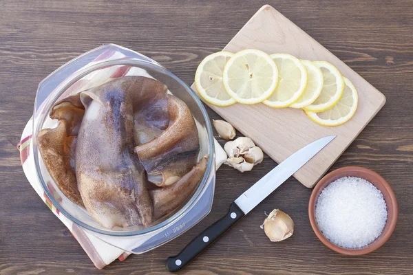 Otlar ve dilimlenmiş limon ile bir cam kapta taze kalamar karkas — Stok fotoğraf