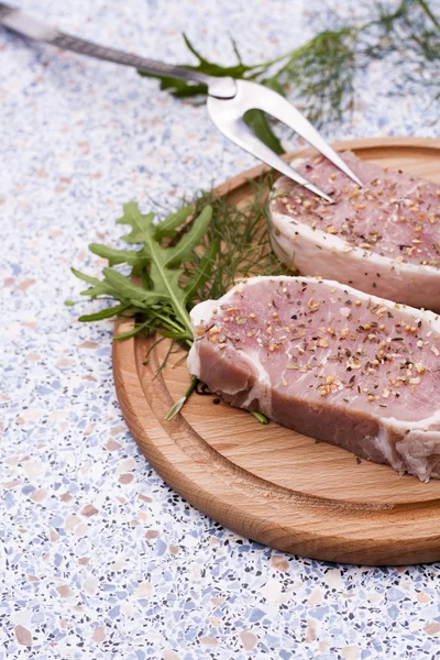 Färsk rå kött med blanksteg och örter på träplatta i tabell — Stockfoto