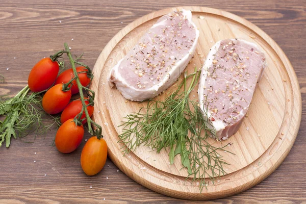 Verse rauwe biefstuk vlees met spaties, kruiden en groenten op houten tafel — Stockfoto