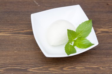 Mozzarella with herbs in a white rectangular bowl on wooden table
