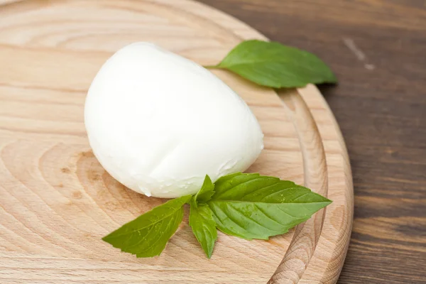Mozzarella with herbs on a round wooden board — Stock Photo, Image