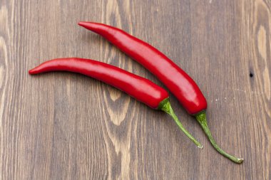 Red chilli pepper with green basil on wooden board, selective focus
