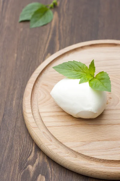 Mozzarella with herbs on a round wooden board, selective focus — 스톡 사진