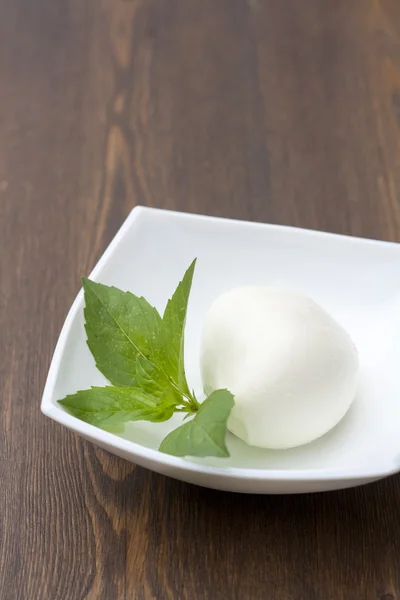 Mozzarella with herbs in a white rectangular bowl on wooden table, selective focus — ストック写真
