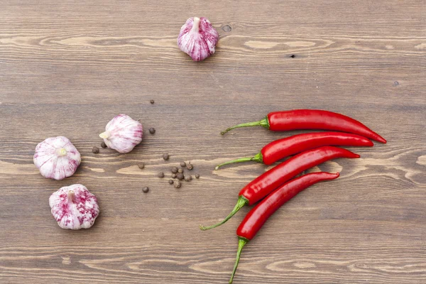 Red chilli pepper and garlic with green basil on wooden table, selective focus — Stok fotoğraf