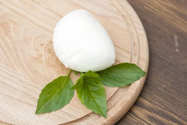 Mozzarella with herbs on a round wooden board, selective focus — ストック写真