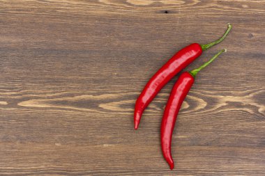 Red chilli pepper with green basil on wooden board, selective focus