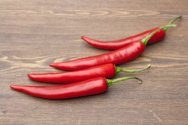 Red chilli pepper with green basil on wooden board, selective focus