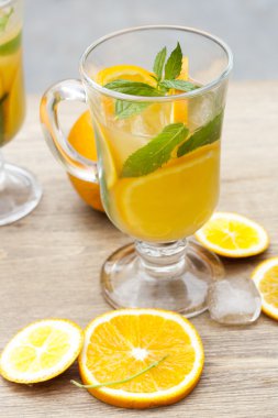 Orange fresh drinks with ice and mint on wooden table, selective focus