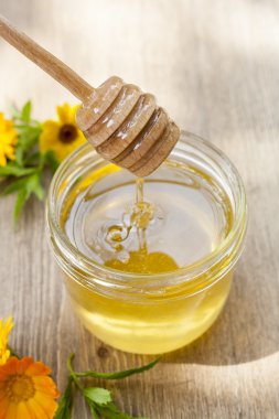 Linden honey in jar and calendula blossoms on wooden table, selective focus