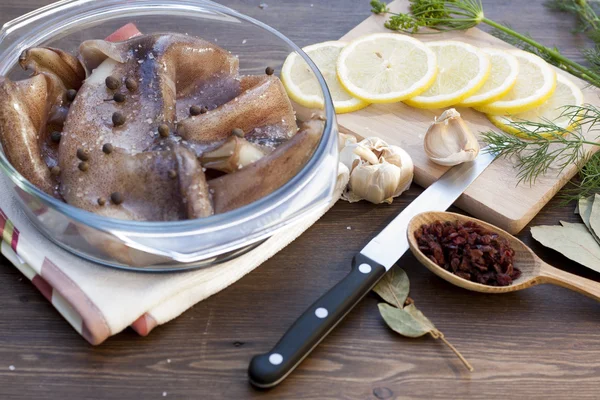 Fresh squid carcass in a glass pot with herbs and sliced lemon, selective focus — Stock Photo, Image