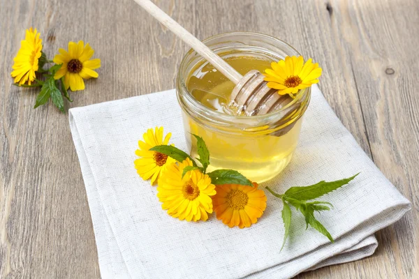 Linden honey in jar and calendula blossoms on wooden table, selective focus — Stok fotoğraf