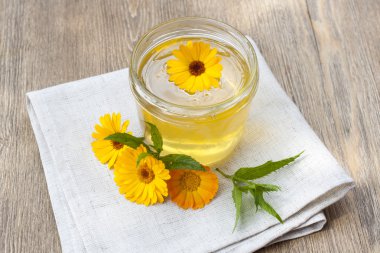 Linden honey in jar and calendula blossoms on wooden table, selective focus