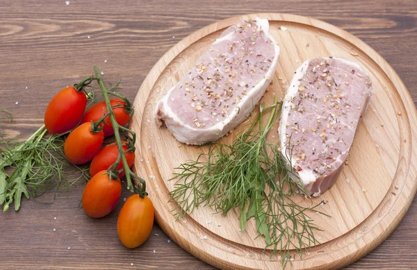 Verse rauwe biefstuk vlees met spaties, kruiden en groenten op houten bord, selectieve aandacht — Stockfoto