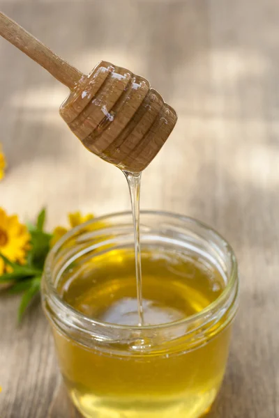 Linden honey in jar and calendula blossoms on wooden table, selective focus — Stok fotoğraf