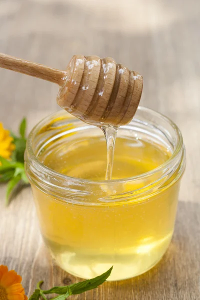 Linden honey in jar and calendula blossoms on wooden table, selective focus — Stock Fotó