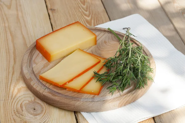 Sliced cheese on wooden board with dill and rosemary, selective focus — ストック写真