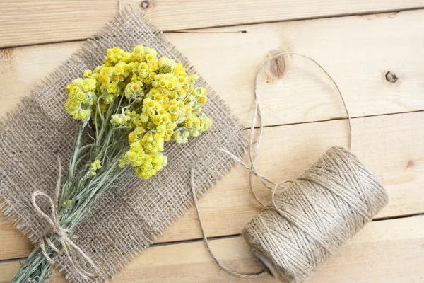 Dwarf everlast flowers bouquet, napkin and twine bobbin on light wooden table, selective focus — Stock Photo, Image