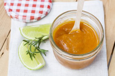 Ev yapımı kayısı reçeli ve taze kayısı, limon ve biberiye yaprakları üzerinde ahşap masa ile