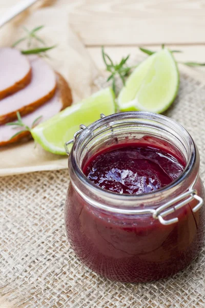 Huisgemaakte confiture organische cherry jam, gerookt vlees en kalk op een houten tafel — Stockfoto