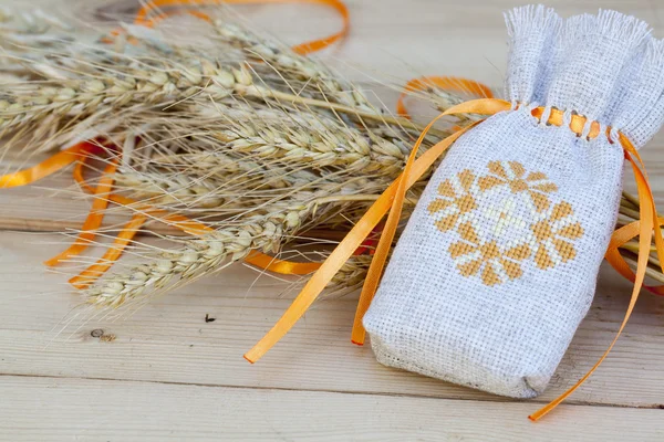 Sachet with ukrainian embroidery, wheat and oat on wooden background — Stock Photo, Image