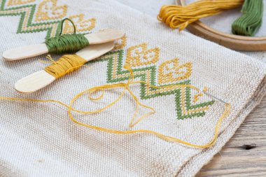 Ukrainian embroidery on the linen fabric and thread embroidery on a wooden table, selective focus