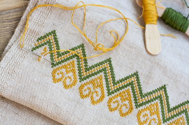 Ukrainian embroidery on the linen fabric and thread embroidery on a wooden table, selective focus