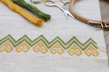 Ukrainian embroidery on the linen fabric and thread embroidery on a wooden table, selective focus