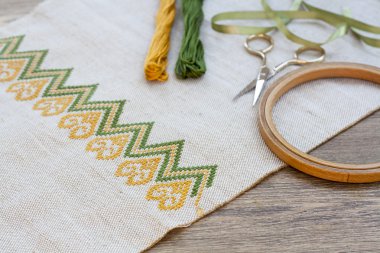 Ukrainian embroidery on the linen fabric and thread embroidery on a wooden table, selective focus