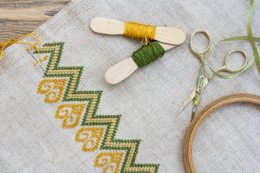 Ukrainian embroidery on the linen fabric and thread embroidery on a wooden table, selective focus