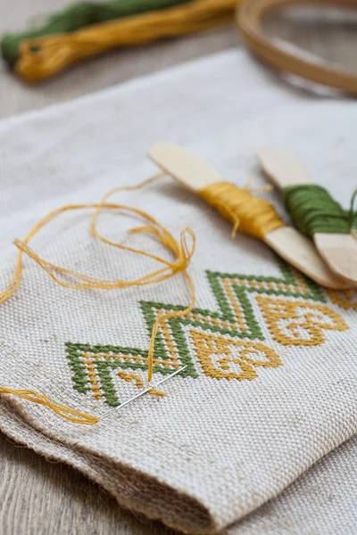 Ukrainian embroidery on the linen fabric and thread embroidery on a wooden table, selective focus — Stockfoto