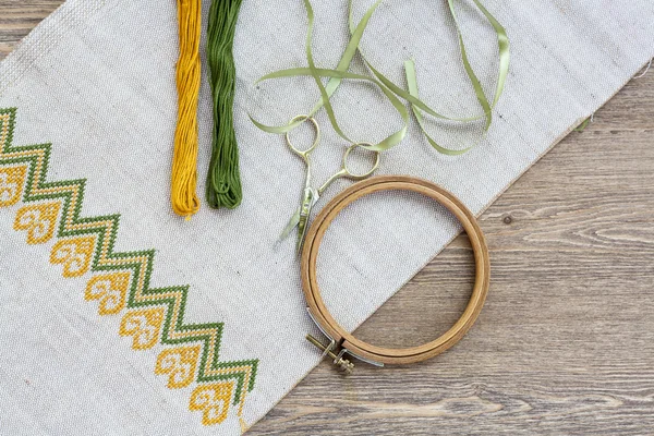 Ukrainian embroidery on the linen fabric and thread embroidery on a wooden table, selective focus — Stock Photo, Image