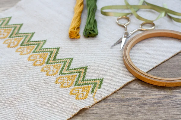 Ukrainian embroidery on the linen fabric and thread embroidery on a wooden table, selective focus — Stock Photo, Image