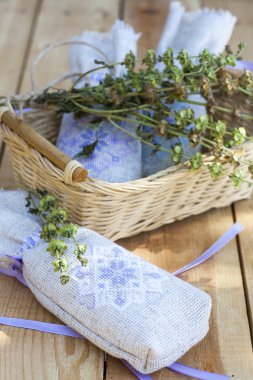 Sachet with ukrainian embroidery, sheaf of wheat and dried herbs on wooden background, close-up selective focus