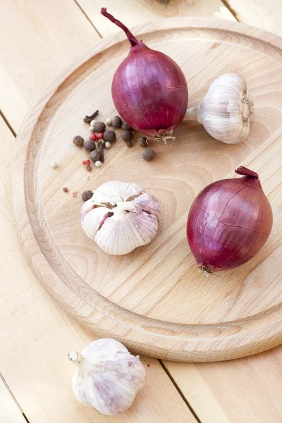 Red onion and garlic bulbs on wooden board close-up, selective focus — Zdjęcie stockowe