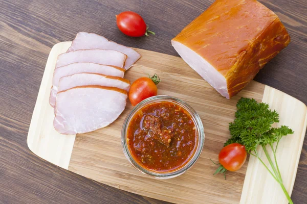 Homemade tomato sauce in glass jar with tasty ham smoked whole and sliced close-up, selective focus — Stock Fotó