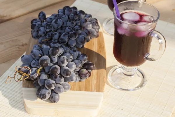 Grape juice cooler with ice in glass and glass of fresh blue grapes on a wooden table close-up, selective focus — Φωτογραφία Αρχείου