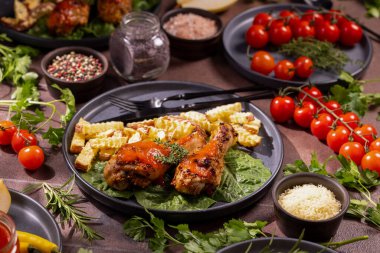 Bitki ve sosla tatlandırılmış kızarmış tavuk budu taze sebzelerden oluşan bir yatakta kızartılmış patates kızartması ile servis ediliyor. Yanında da akşam yemeği için olgun domates ve baharatlar var.