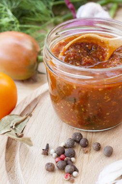 Homemade tomato sauce in glass jar with fresh tomatos, garlic, onion, herbs and spices, close up, selective focus