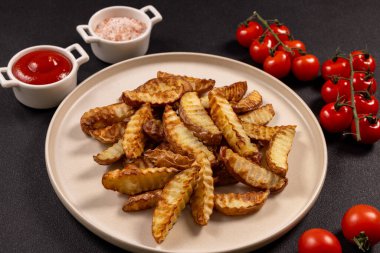 Taze fırınlanmış patates dilimleri bulunan tabakta lezzetli bir aperatif ya da aperatif sunan ketçap ve pembe tuzla tamamlanmış taze kiraz domatesleri taze renklerde.