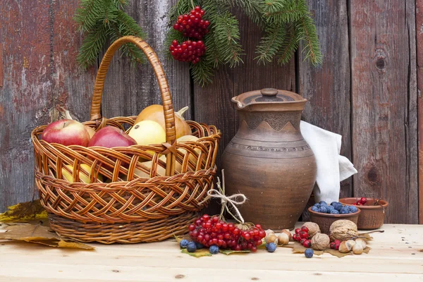 Autumn still life with pumpkins in basket and autumn berry on old wooden background, closeup — Stock Photo, Image