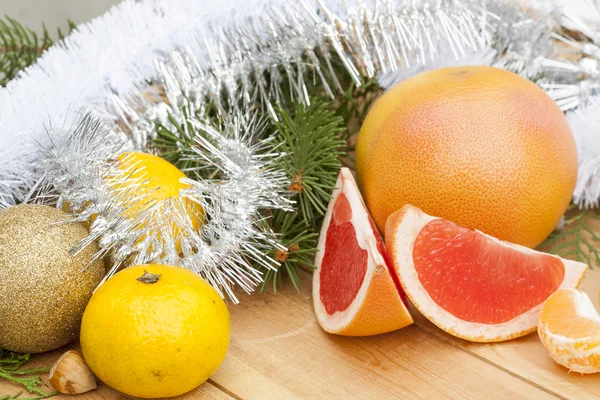 Ripe Cut Red Grapefruit with New Year's and Christmas decoration midst fruits and tinsel — Stock Photo, Image