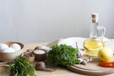 Gıda katkı maddeleri. Yağ, yumurta, sarımsak ve ahşap masa üzerinde otlar. Ahşap tahta ve peçete.