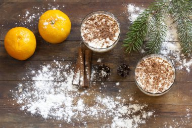 Vanilla panna cotta with chocolate, tangerines, cones, cinnamon and nuts in Christmas decor with Christmas tree on colorful background bokeh